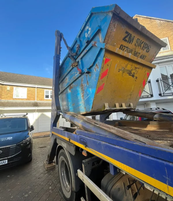 ZM Skips hydraulic truck collecting blue skip at Berridge Mews West Hampstead NW6 1RF London