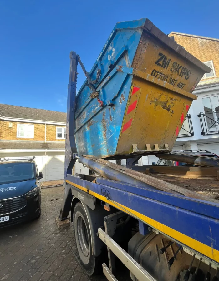 ZM Skips hydraulic truck collecting blue skip at Berridge Mews West Hampstead NW6 1RF London